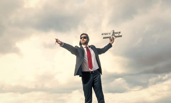 successful businessman in suit and pilot hat launch plane toy on sky background.