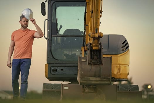 Worker with bulldozer on site construction. Man excavator worker. Construction driver worker with excavator on the background. Construction worker with tractor or construction vehicle at building