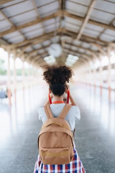 Asian teenage girl african american traveling using a camera take a photo to capture memories while waiting for a train at the station