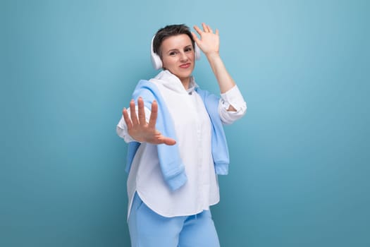 dude young woman with a short haircut is relaxing under a playlist in headphones on a studio background with copy space.