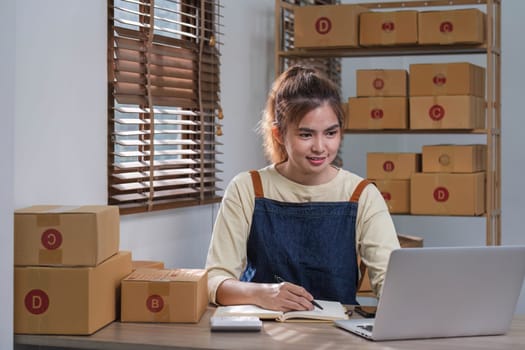 Portrait of Asian young woman SME working with a box at home the workplace.start-up small business owner, small business entrepreneur SME or freelance business online and delivery concept...