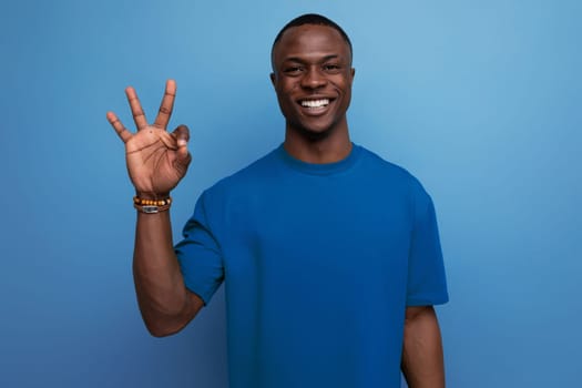 young friendly american man in a t-shirt on a blue background with copy space. people lifesal concept.