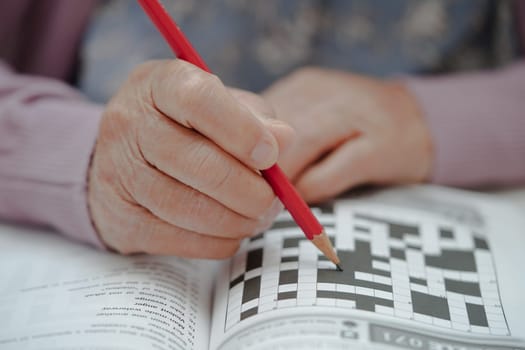 Asian elderly woman playing sudoku puzzle game to practice brain training for dementia prevention, Alzheimer disease.