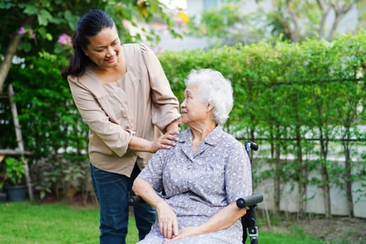 Caregiver help Asian elderly woman disability patient sitting on wheelchair in park, medical concept.