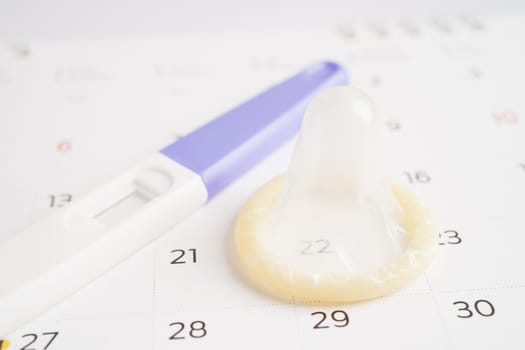 Pregnancy test and condom for female on calendar, ovulation day.