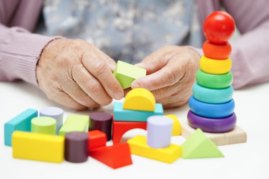 Asian elderly woman playing puzzles game to practice brain training for dementia prevention, Alzheimer disease.
