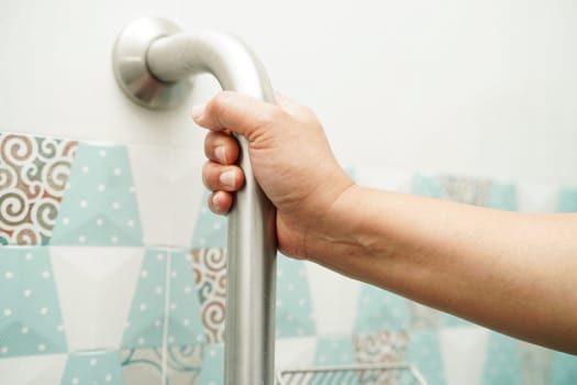 Asian woman patient use toilet support rail in bathroom, handrail safety grab bar, security in nursing hospital.