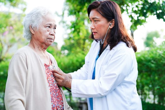 Doctor help Asian elderly woman disability patient walk with walker in park, medical concept.