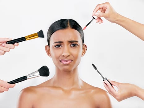 Makeup, brush and anxiety, woman with beauty shine and overwhelmed with beautician on white background. Doubt with cosmetics, tools and hands crowd female model in studio, cosmetology and skin glow.