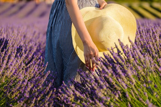 Amidst the fragrant of a lavender field, a girl's hands lovingly hold a straw hat.