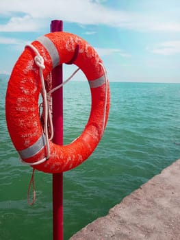 Lifebuoy on the background of the azure sea, sea pier in the sea, close-up, vertical.