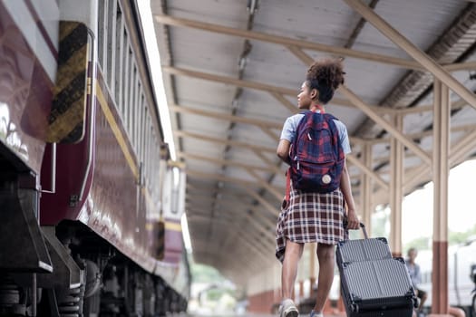 Young female traveler walking standing with a suitcase at train station. woman traveler tourist walking standing smiling with luggage at train station. High quality photo