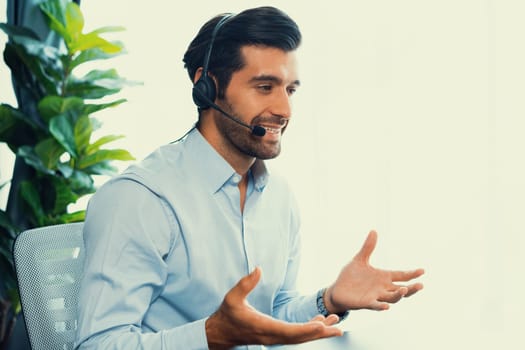 Male call center operator or telesales representative siting at his office desk wearing headset and engaged in conversation with client providing customer service support or making a sale. fervent