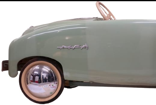 Close up detail of the front end of a mint green MFA pedal car with shiny round hubcaps, a vintage toy for children made in France. Isolated on white with clipping path