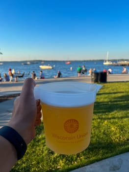 MADISON, WISCONSIN, JULY 16 2022: Holding a jug of beer during summer sunset at Madison Memorial Union. High quality photo