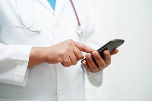 Asian woman doctor holding mobile phone or tablet for search method of treatment patient in hospital.