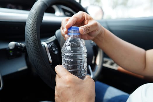 Asian woman driver hold drink in car, dangerous and risk an accident.