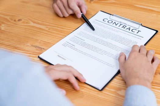 Businessman carefully reviewing contract document for corporate partnership. Client reading agreement deal and terms on meeting table for professional business decision. Entity