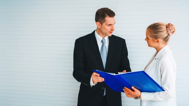 Two business people talk project strategy at office meeting room. Businessman discuss project planning with colleague at modern workplace while having conversation and advice on financial report. Jivy