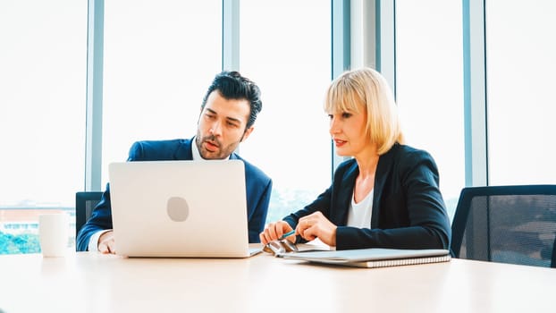 Two business people talk project strategy at office meeting room. Businessman discuss project planning with colleague at modern workplace while having conversation and advice on financial report. Jivy