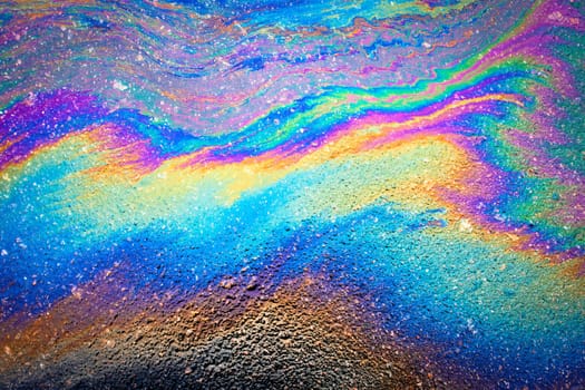 Oil spill on dark asphalt, parking lot.Abstract background from motor oil, gas or petrol spilled on asphalt.Spilled oil on the asphalt road background.