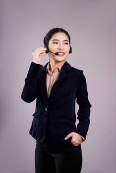 Attractive asian female call center operator with happy smile face advertises job opportunity on empty space, wearing a formal suit and headset on customizable isolated background. Enthusiastic