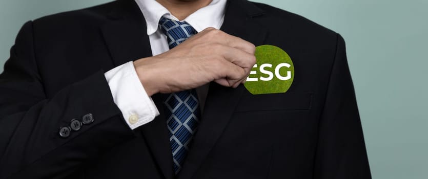 Corporate promoting sustainable and green business concept with businessman holding ESG symbol paper as environmental social government commitment using clean energy with zero CO2 emission. Alter