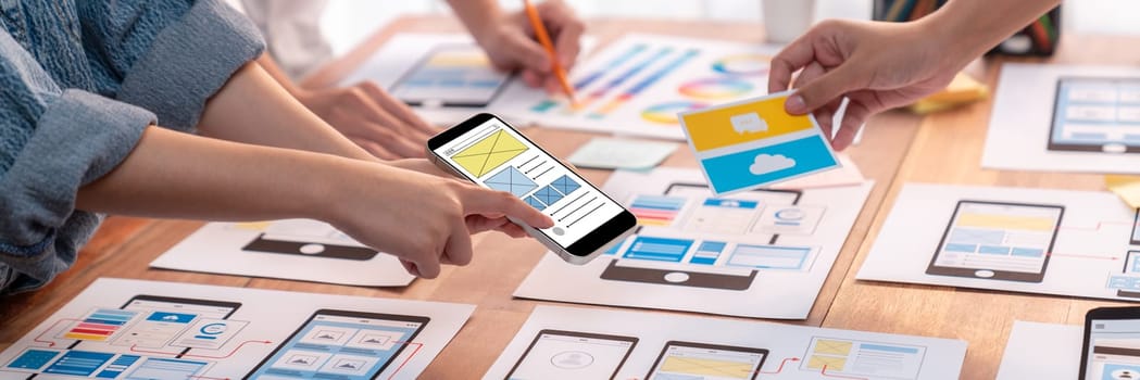 Panorama shot of front-end developer team brainstorming UI and UX designs for mobile app on paper wireframe interface. User interface development team planning for user-friendly UI design. Scrutinize