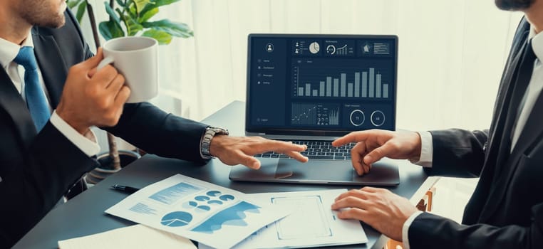 Closeup busy analyst team with coffee discuss financial data on digital dashboard, analyzing chart and graph using business technology display on laptop screen. Fintech business intelligence. Fervent