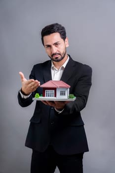 Real estate agent hold house model sample on isolated background. Housing business showcase with copy space. Realtor presenting property investment opportunity on house loan idea. Fervent