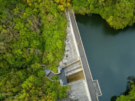 Aerial view of concrete dam and reservoir in green forest. High quality photo