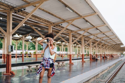 Asian teenage girl african american traveling using a camera take a photo to capture memories while waiting for a train at the station