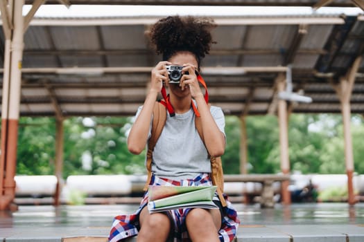 Asian teenage girl african american traveling using a camera take a photo to capture memories while waiting for a train at the station