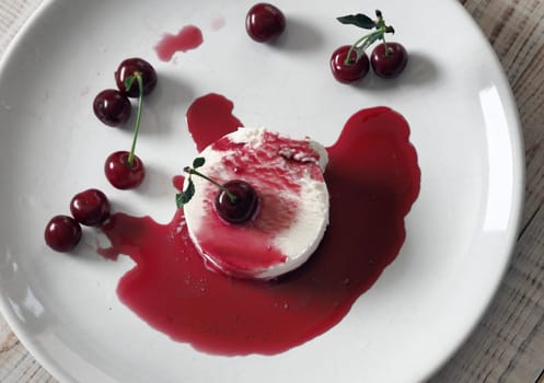 Food background.Ice cream with cherries on a white plate, poured with red jam.Top view