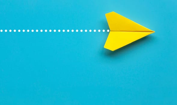 Top view of yellow paper airplane on blue background with customizable space for text