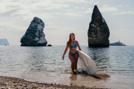 Close up shot of beautiful young caucasian woman with black hair and freckles looking at camera and smiling. Cute woman portrait in a pink bikini posing on a volcanic rock high above the sea