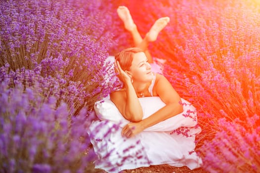 Woman lavender field. A middle-aged woman lies in a lavender field and enjoys aromatherapy. Aromatherapy concept, lavender oil, photo session in lavender.