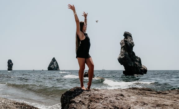 Woman travel sea. Young Happy woman in a long red dress posing on a beach near the sea on background of volcanic rocks, like in Iceland, sharing travel adventure journey