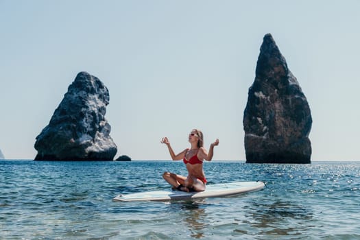 Close up shot of beautiful young caucasian woman with black hair and freckles looking at camera and smiling. Cute woman portrait in a pink bikini posing on a volcanic rock high above the sea