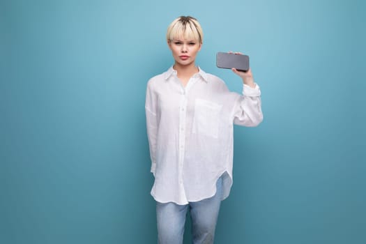 young smart blond career woman in a white shirt shows ads on a smartphone with a mockup. business concept.