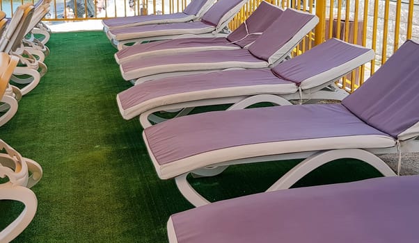 Free deck chairs stand in a row, empty beach chairs are waiting for tourists.