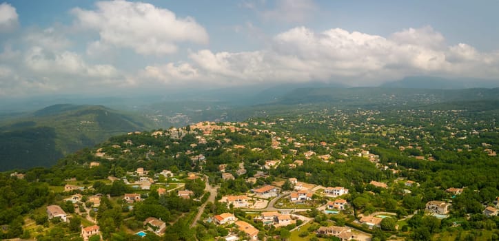 French villas dot beautiful green landscape outside village on sunny day. High quality photo