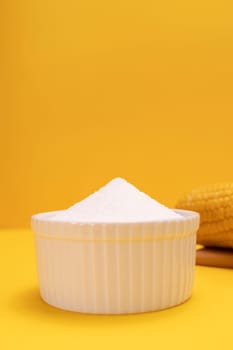 Natural organic sweetener Erythritol, produced by fermentation from corn, called dextrose in ceramic bowl on yellow orange background. Sugar substitute. Vertical plane, copy space for text.