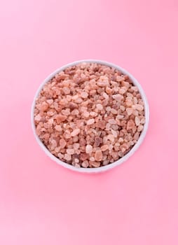 Flatly Pink Himalayan Rock Salt, Halite In White Ceramic Bowl On Pink Background. Top View Vertical Plane, Copy Space For Text. High quality photo.