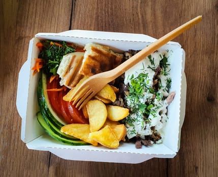 Street food in a disposable paper container and a disposable fork. High quality photo