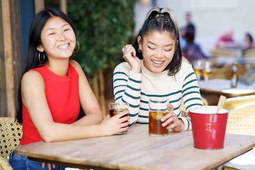 Two young Chinese girls having a drink on the terrace of a typical bar in Granada. Concept of Asian people traveling in Europe.