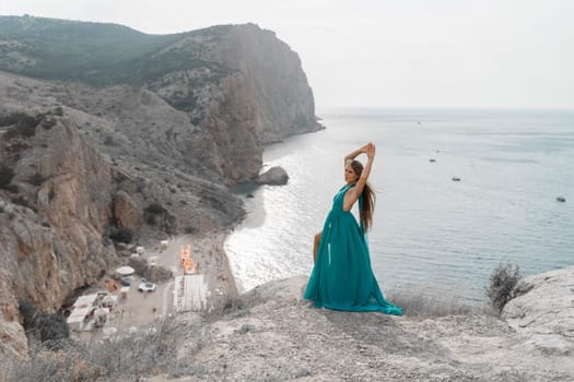 Woman sea green dress. Side view a happy woman with long hair in a long mint dress posing on a beach with calm sea bokeh lights on sunny day. Girl on the nature on blue sky background