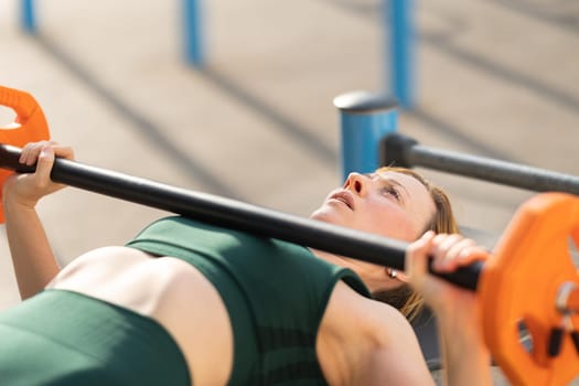 Adult fitness woman training her hands with lifting dumbbell. Mid shot