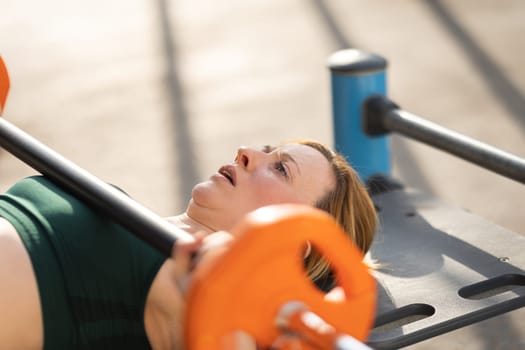 Adult fitness woman training her hands lifting dumbbell. Mid shot