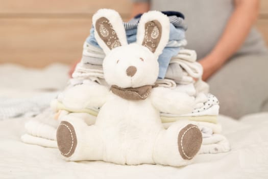 Pile of baby clothes, rabbit and pregnant woman